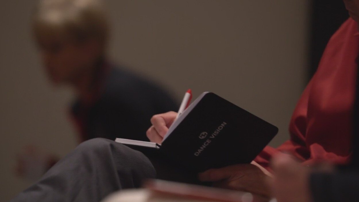 Attendee taking notes on her Dance Vision Notebook at a dance workshop